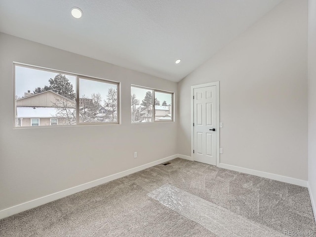 carpeted spare room with vaulted ceiling