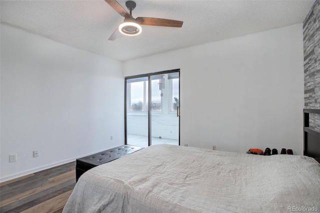 bedroom with ceiling fan, access to exterior, a textured ceiling, and dark hardwood / wood-style flooring