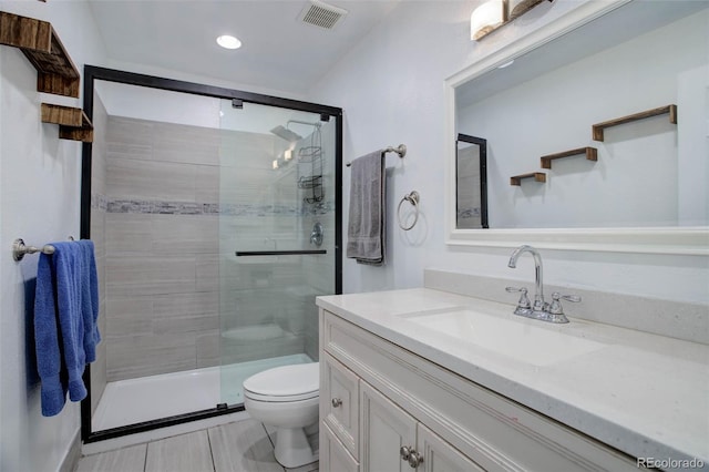 bathroom featuring a shower with door, toilet, vanity, and tile patterned flooring