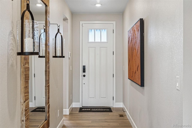doorway featuring baseboards and wood finished floors