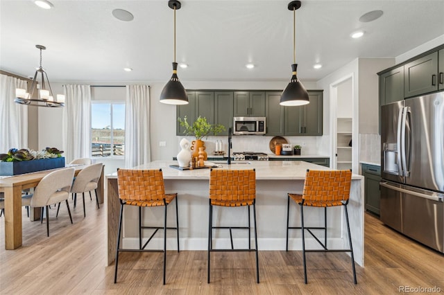 kitchen featuring a breakfast bar, backsplash, light wood-type flooring, and appliances with stainless steel finishes