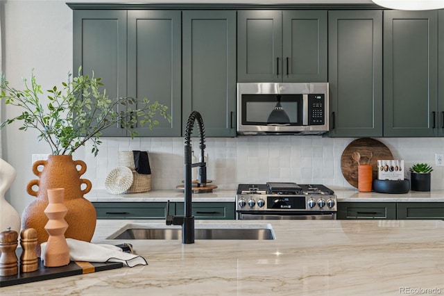 kitchen with green cabinetry, stainless steel appliances, and a sink
