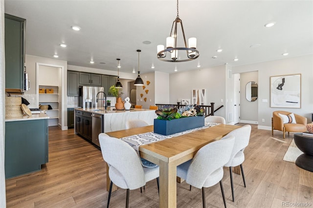 dining space with baseboards, light wood finished floors, a chandelier, and recessed lighting