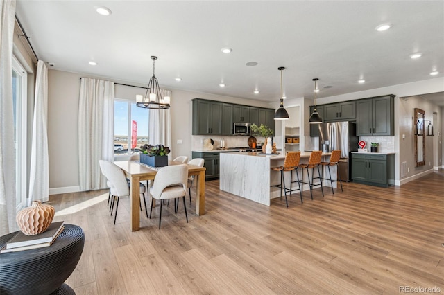 dining area with an inviting chandelier, light wood-style flooring, baseboards, and recessed lighting