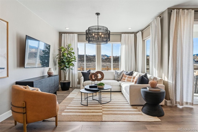 living room featuring wood finished floors, baseboards, and a notable chandelier