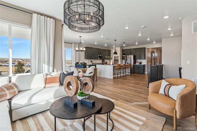 living area with a notable chandelier, visible vents, recessed lighting, and light wood-style floors
