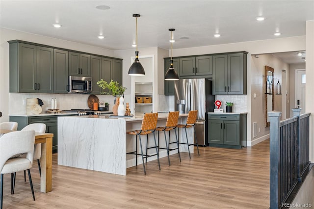 kitchen with stainless steel appliances, decorative light fixtures, recessed lighting, light wood finished floors, and backsplash