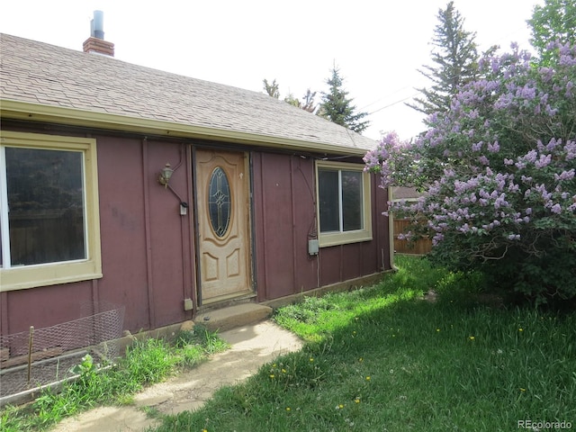 135 E 2nd St, Nederland, CO 80466 - view of exterior entry featuring a shingled roof, a chimney, and board and batten siding