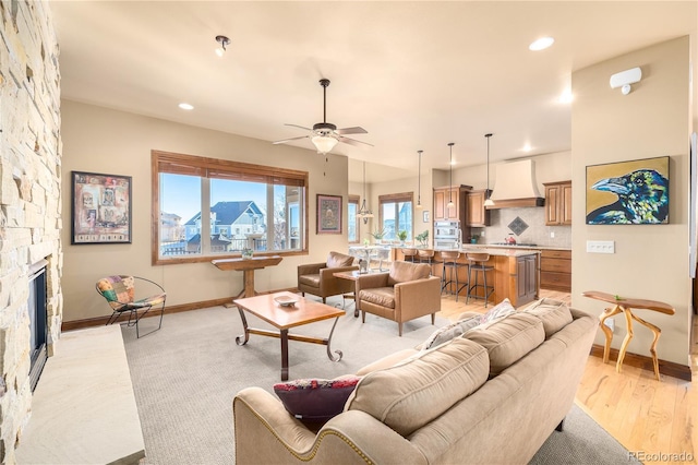 living room featuring ceiling fan, light hardwood / wood-style floors, and a fireplace