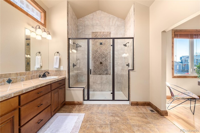 bathroom featuring vanity, a shower with shower door, and vaulted ceiling