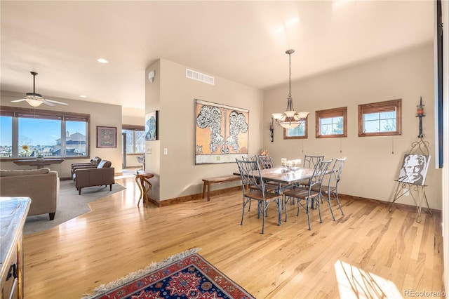 dining area with ceiling fan with notable chandelier and light hardwood / wood-style flooring