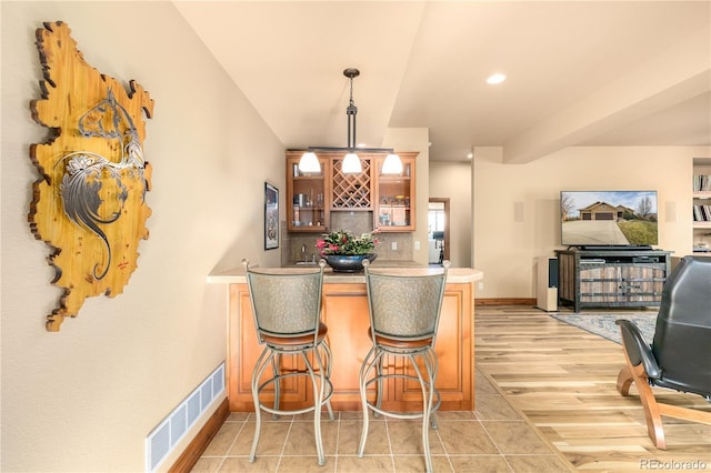 kitchen featuring decorative light fixtures, kitchen peninsula, a breakfast bar area, and light hardwood / wood-style flooring