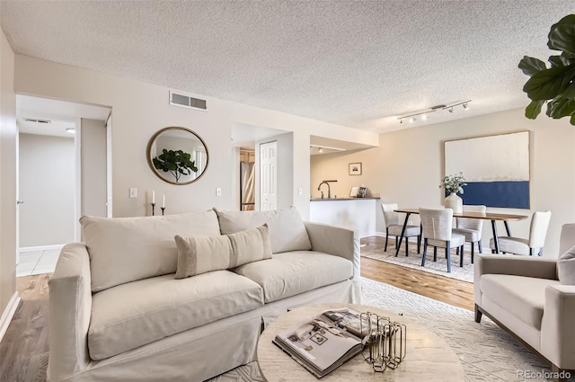 living area with wood finished floors, a textured ceiling, and baseboards