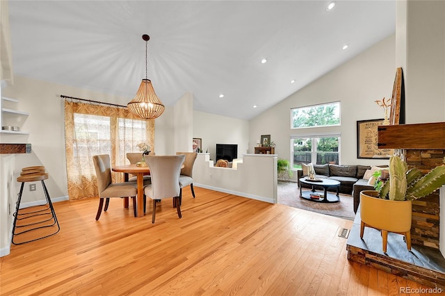 dining room with light wood-style flooring, high vaulted ceiling, a chandelier, recessed lighting, and baseboards