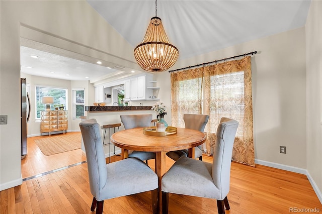 dining area featuring light wood-style flooring, baseboards, and a chandelier