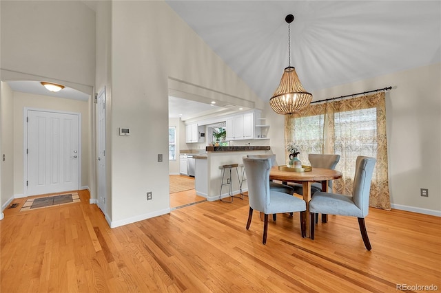 dining room featuring light wood-style floors, baseboards, a chandelier, and high vaulted ceiling