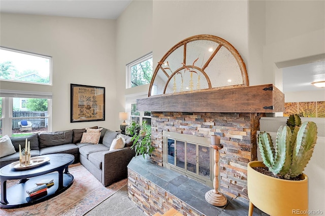 living room with a high ceiling, plenty of natural light, and a fireplace