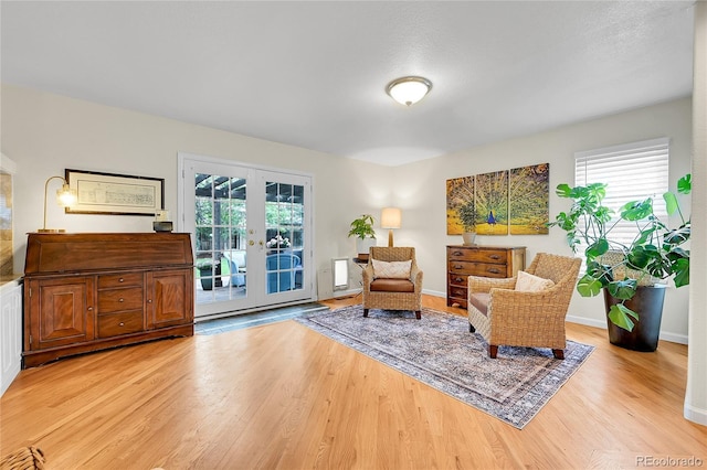 sitting room with french doors, light wood finished floors, and baseboards