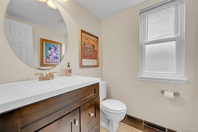 half bath featuring vanity, toilet, and baseboards