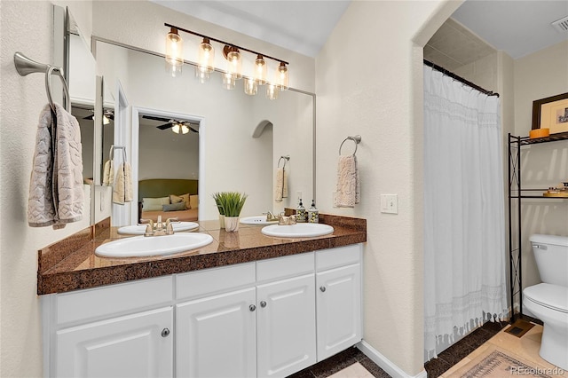 full bath featuring toilet, double vanity, ceiling fan, tile patterned floors, and a shower with curtain