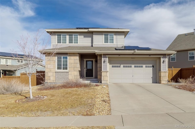 view of front of house featuring driveway, stone siding, fence, and solar panels