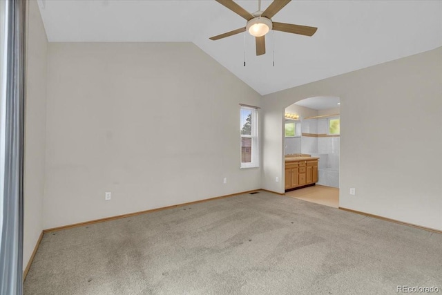 5960 S Estes St, Littleton, CO 80123 - spare room featuring arched walkways, ceiling fan, vaulted ceiling, light colored carpet, and baseboards