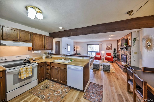 kitchen featuring light hardwood / wood-style flooring, kitchen peninsula, sink, a textured ceiling, and white appliances