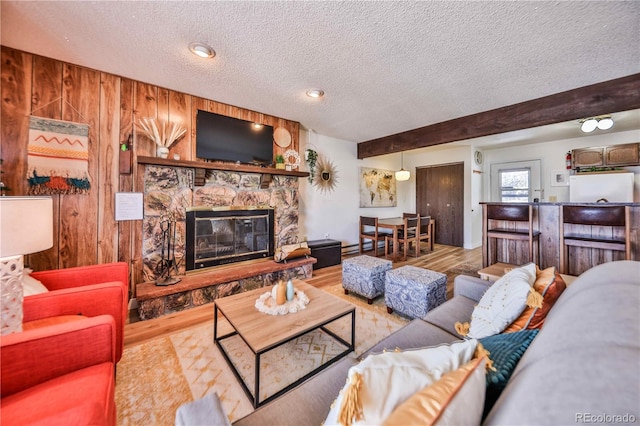 living room with hardwood / wood-style flooring, a stone fireplace, and a textured ceiling