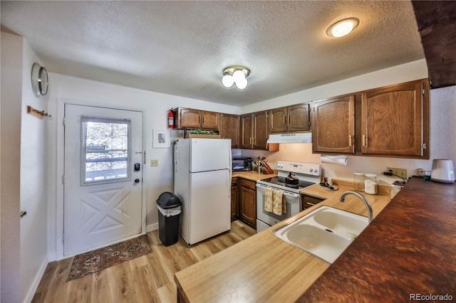 kitchen with a textured ceiling, sink, light wood-type flooring, and white appliances