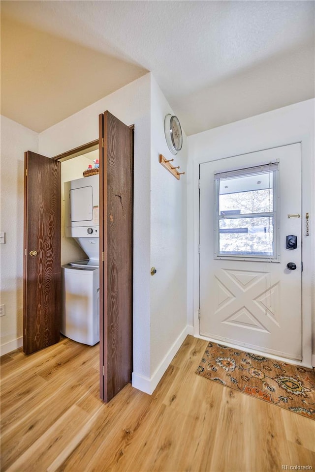 doorway to outside featuring stacked washer and clothes dryer and light wood-type flooring