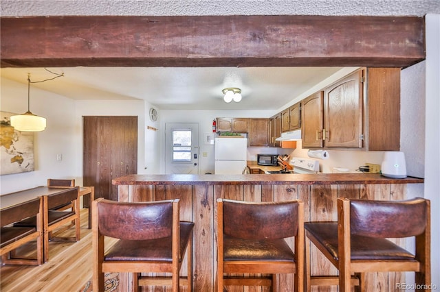 kitchen with kitchen peninsula, a kitchen breakfast bar, decorative light fixtures, stove, and white fridge