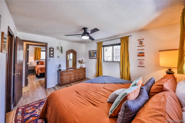 bedroom with light hardwood / wood-style floors, a textured ceiling, and ceiling fan