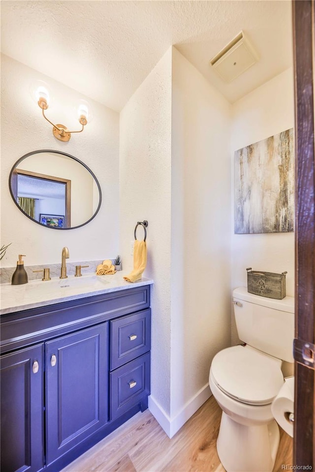 bathroom with vanity, a textured ceiling, hardwood / wood-style flooring, and toilet