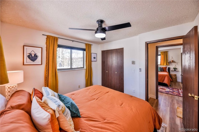 bedroom featuring dark hardwood / wood-style flooring, a textured ceiling, a closet, and ceiling fan