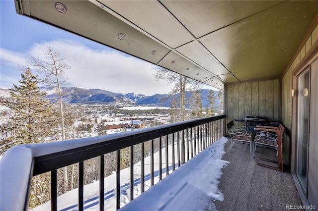 snow covered back of property featuring a mountain view