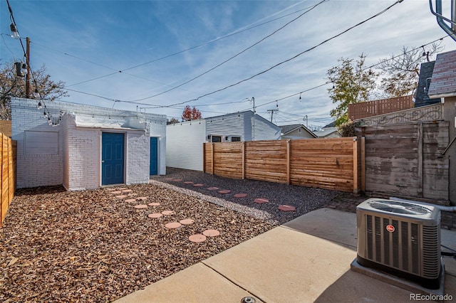 view of yard featuring a fenced backyard, a shed, central AC, and an outdoor structure