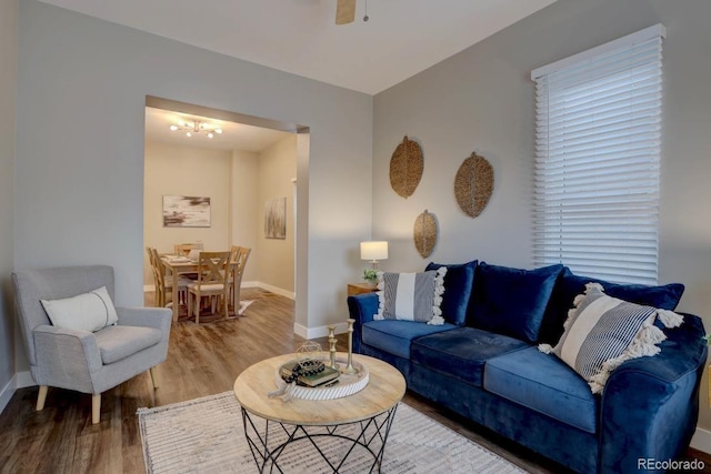 living area with a ceiling fan, baseboards, and wood finished floors