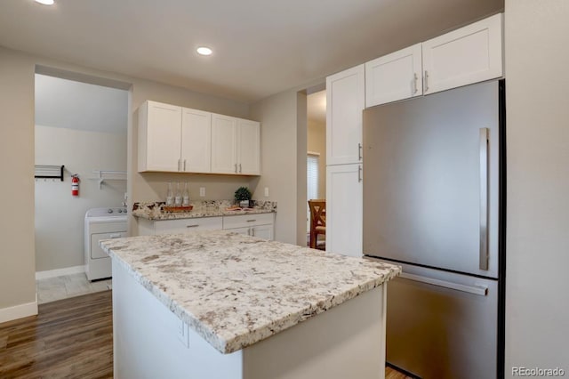 kitchen with wood finished floors, baseboards, white cabinets, freestanding refrigerator, and washer / clothes dryer