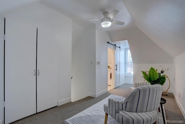 living area featuring lofted ceiling, ceiling fan, a barn door, carpet flooring, and baseboards