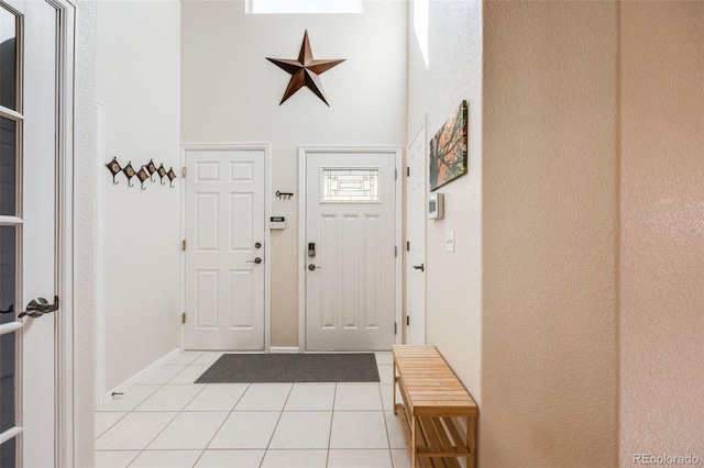 foyer entrance featuring light tile patterned floors and a towering ceiling