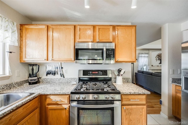 kitchen featuring sink, light stone countertops, light tile patterned floors, and stainless steel appliances