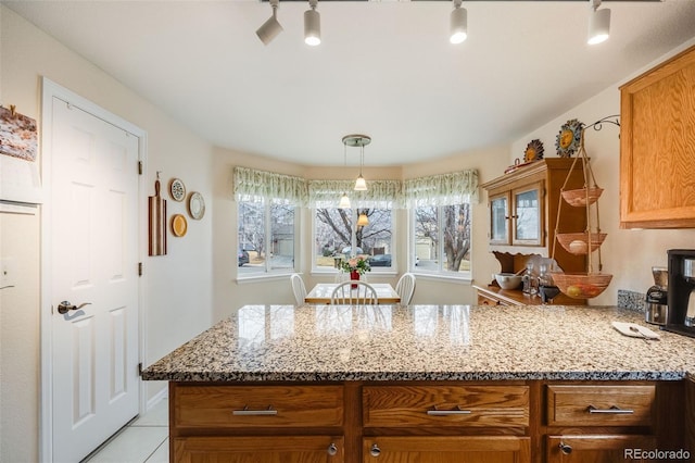 kitchen with kitchen peninsula, light stone countertops, light tile patterned floors, and track lighting