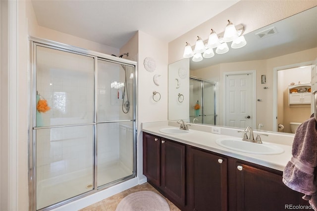 bathroom featuring tile patterned flooring, vanity, toilet, and a shower with door