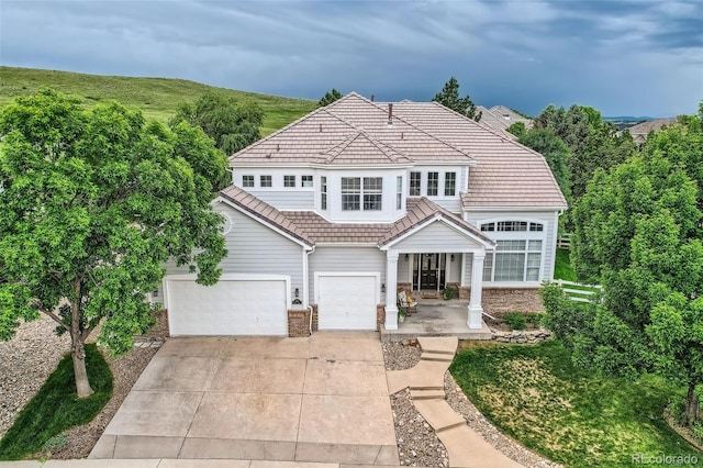 7866 Witney Pl, Lone Tree, CO 80124 - view of front of home featuring a tiled roof, driveway, a porch, and an attached garage