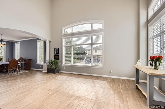 7866 Witney Pl, Lone Tree, CO 80124 - entrance foyer with arched walkways, a high ceiling, light wood-style floors, ornamental molding, and decorative columns