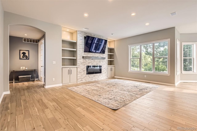 7866 Witney Pl, Lone Tree, CO 80124 - unfurnished living room with arched walkways, built in features, a fireplace, light wood-type flooring, and recessed lighting
