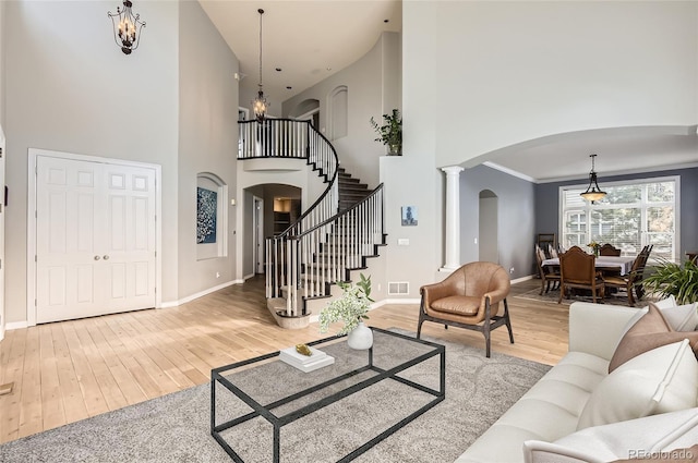 7866 Witney Pl, Lone Tree, CO 80124 - living room with arched walkways, a towering ceiling, hardwood / wood-style flooring, a chandelier, and decorative columns