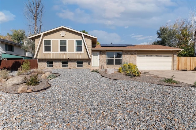 tri-level home featuring a garage and solar panels