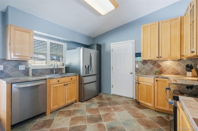 kitchen with backsplash, tile counters, sink, and appliances with stainless steel finishes