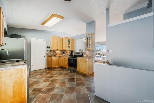 kitchen featuring light brown cabinets, backsplash, sink, vaulted ceiling, and stainless steel appliances